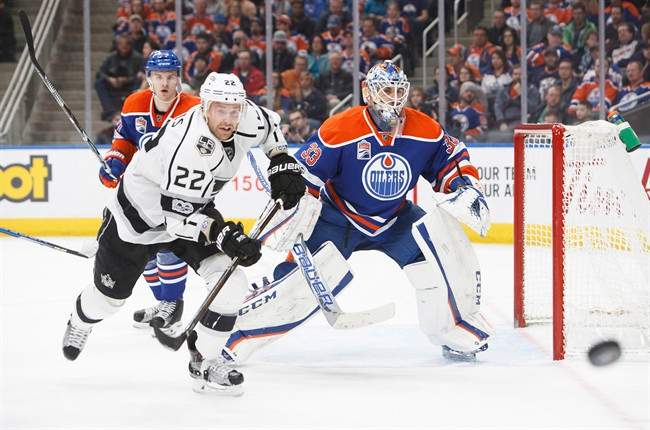 Edmonton Oilers' goaltender Cam Talbot (33) keeps his eye on the puck as Los Angeles Kings' Trevor Lewis (22) races for possession during third period NHL action in Edmonton, Alta., on Monday, March 20, 2017. 