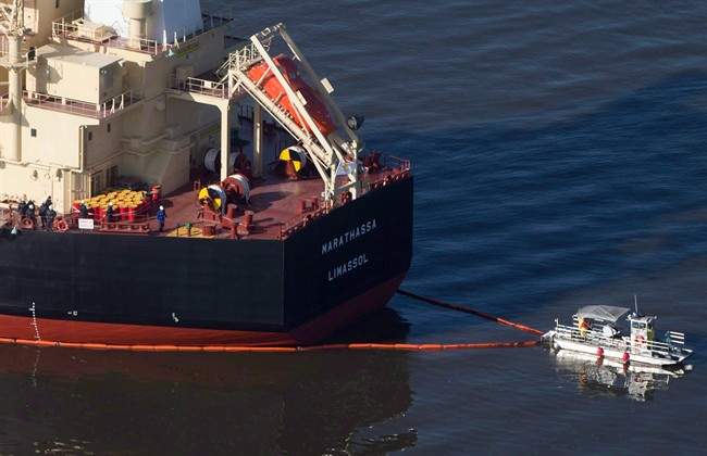 A spill response boat secures a boom around the bulk carrier cargo ship MV Marathassa after a bunker fuel spill in Vancouver, B.C., on April 9, 2015. Charges have been laid against the owners of the MV Marathassa nearly two years after a leak of bunker fuel onto the beaches of English Bay in Vancouver. 