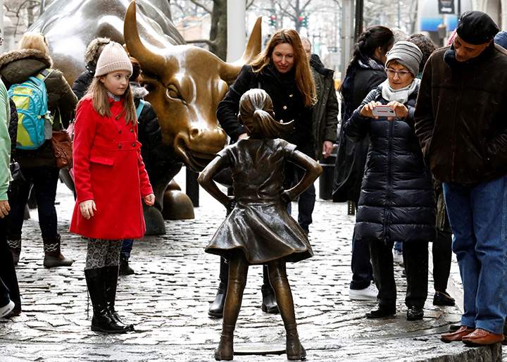 People look at a statue of a girl facing the Wall St. Bull in the financial district in New York, U.S., March 7, 2017.