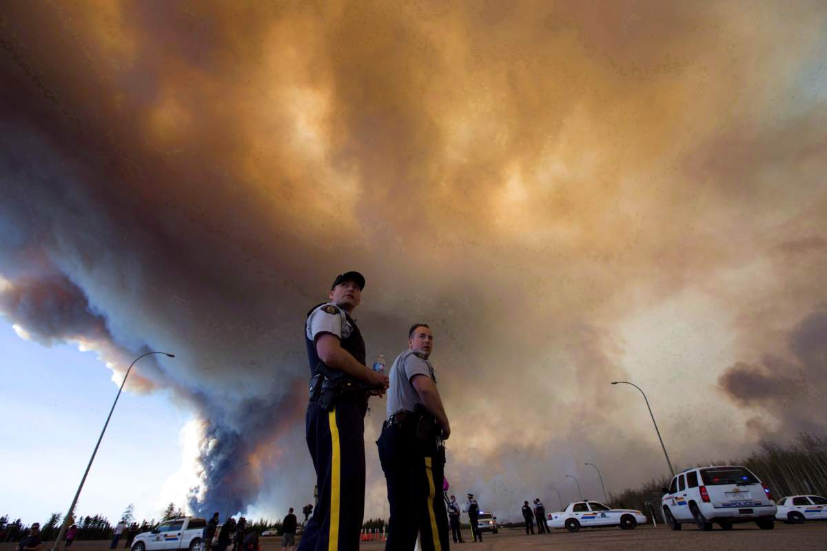 Police officers direct traffic under a cloud of smoke from a wildfire in Fort McMurray, Alta., on Friday, May 6, 2016. The photo earned photographer Jason Franson a nomination in the News Feature Photo category for the National Newspaper Awards. THE CANADIAN PRESS/Jason Franson