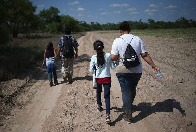 Central American immigrant families walk through the countryside after crossing from Mexico into the United States to seek asylum on April 14, 2016 in Roma, Texas. 