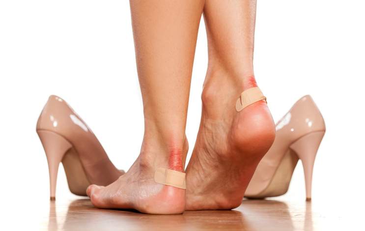 Closeup of  women's heels with a blister plaster on.