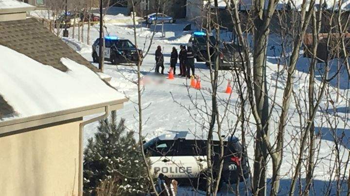 Police officers are seen standing near the body of a driver who was shot by an officer in the Edmonton community of Hodgson on March 9, 2017. The body of the victim has been blurred out.