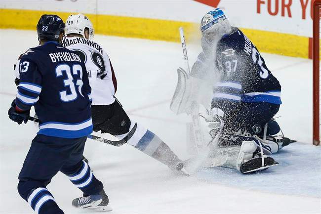 Despite the face-wash by Colorado Avalanche's Nathan MacKinnon (29) Winnipeg Jets goalie Connor Hellebuyck (37) stops the shot as Dustin Byfuglien (33) defends during third period NHL action in Winnipeg on Saturday, March 4, 2017. THE CANADIAN PRESS/John Woods.