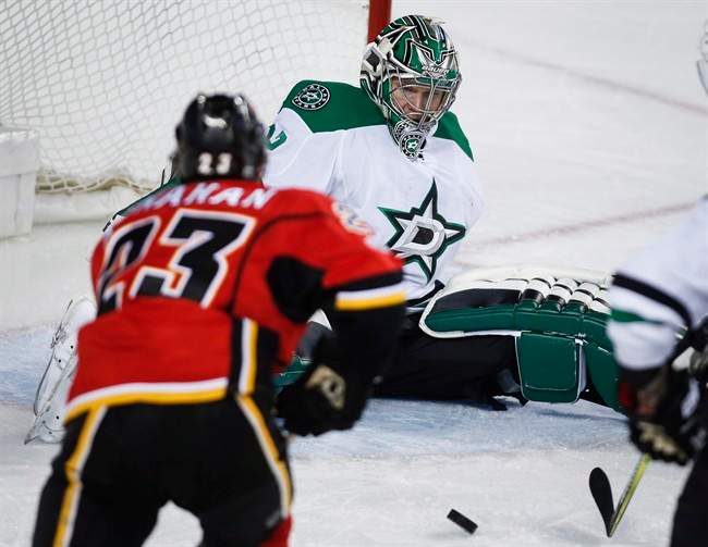 Dallas Stars goalie Kari Lehtonen, right, of Finland, loses his balance as Calgary Flames' Sean Monahan chases as rebound during third period NHL hockey action in Calgary, Friday, March 17, 2017.