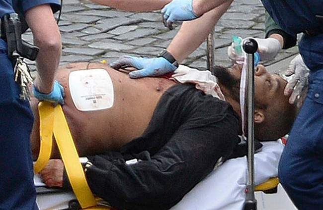 In this March 22, 2017 file photo, the attacker Khalid Masood is treated by emergency services outside the Houses of Parliament London. British Police named on Thursday March 23, 2017, Khalid Masood as The Houses of Parliament attacker. (Stefan Rousseau/PA via AP, File).