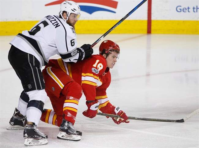 Calgary Flames' Matthew Tkachuk, right, is knocked down by Los Angeles Kings' Jake Muzzin during first period NHL action in Calgary, Alta., Sunday, March 19, 2017. 