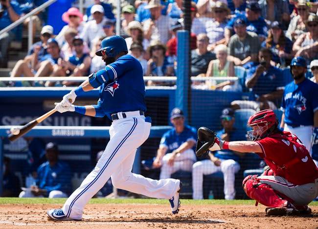 Toronto Blue Jays right fielder Jose Bautista (19) hits a single as Philadelphia Phillies catcher Ryan Hanigan (34) watches during first inning Grapefruit baseball spring training action in Dunedin, Fla., on Thursday, March 2, 2017. 