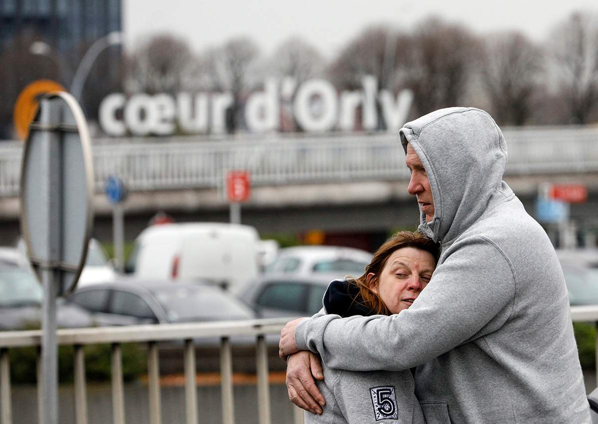Travelers hug outside Orly airport, south of Paris, Saturday, March, 18, 2017.
