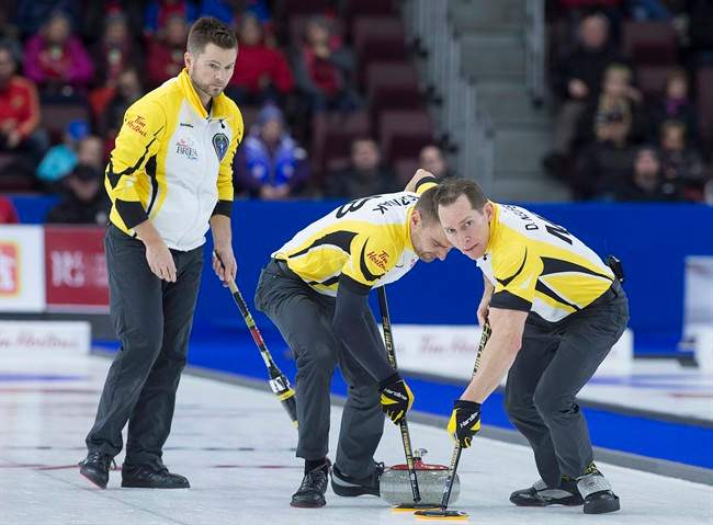 Manitoba skip Mike McEwen, left, follows as Matt Wozniak and Denni Neufeld, right, sweep against Northern Ontario in bronze medal action at the Tim Hortons Brier curling championship at Mile One Centre in St. John's on Sunday, March 12, 2017. 