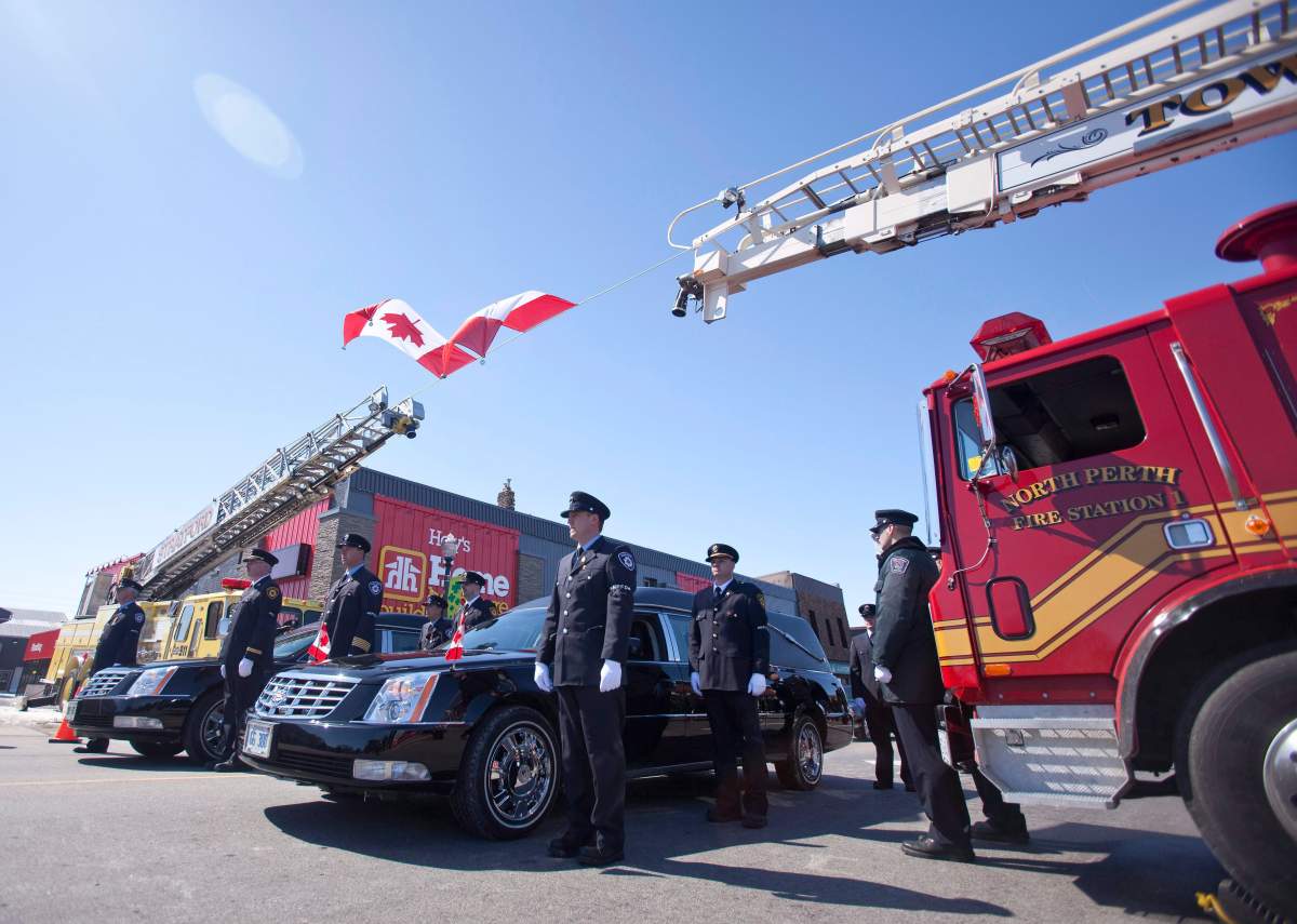 Firefighters escort hearses carrying two fallen colleagues during a funeral procession in Listowel Ontario, March 24, 2011.