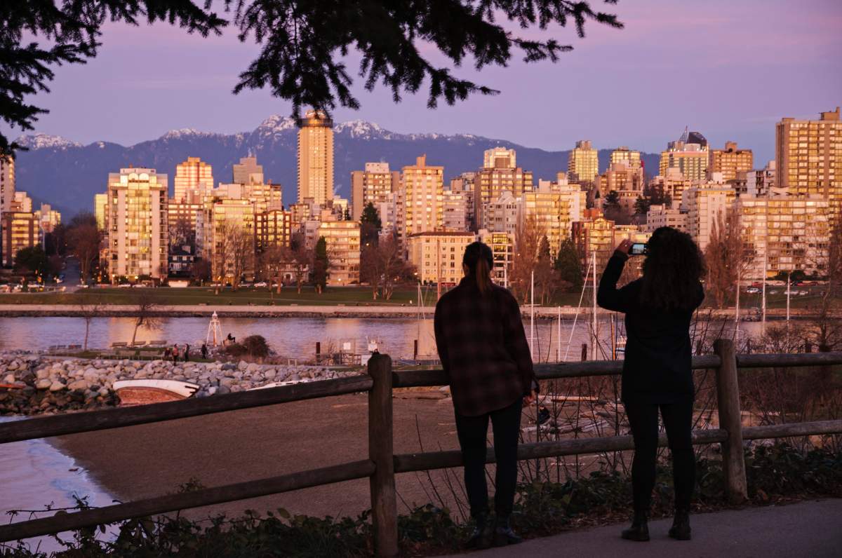 Two women on Kits Point stop to admire the Vancouver skyline; one captures the scene on her smartphone, on Jan. 5, 2014.