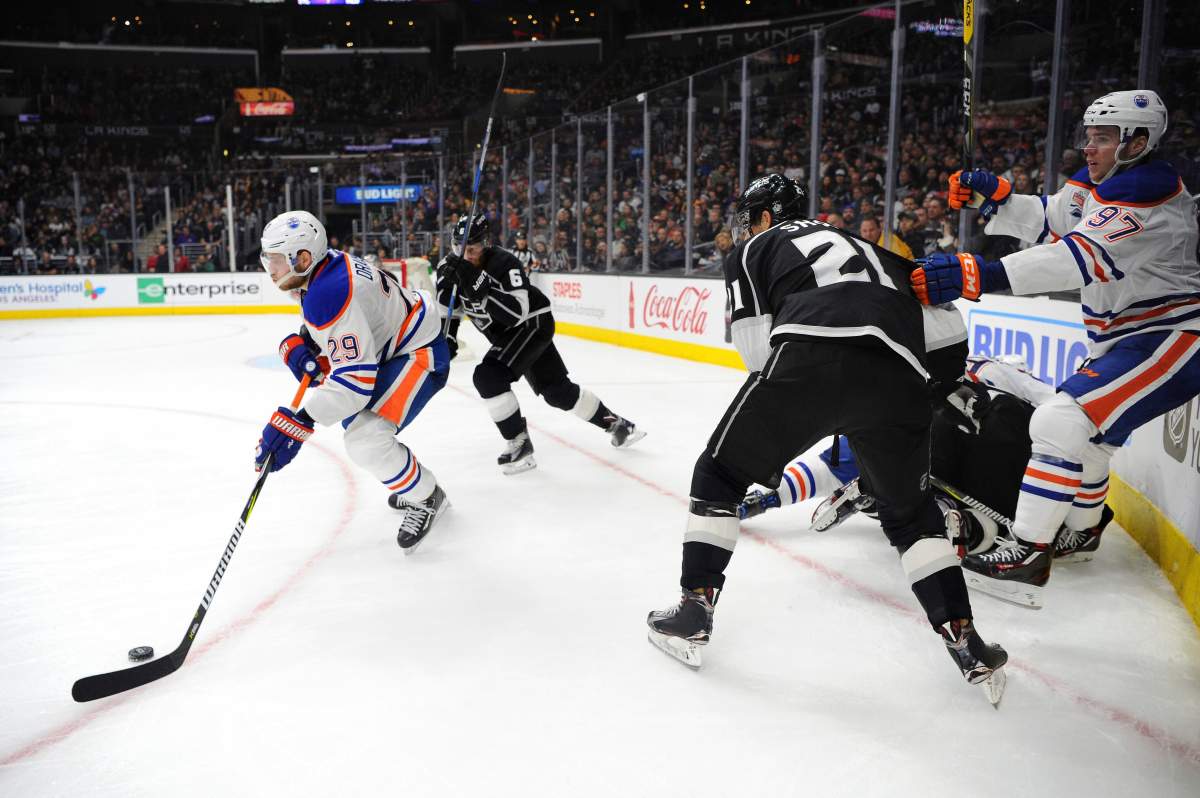 Edmonton Oilers center Leon Draisaitl (29), of Germany, clears the puck from the corner as the Los Angeles Kings defenseman Jake Muzzin (6) pursues in the third period of an NHL hockey game, Tuesday, April 4, 2017, in Los Angeles. The Kings won 6-4.
