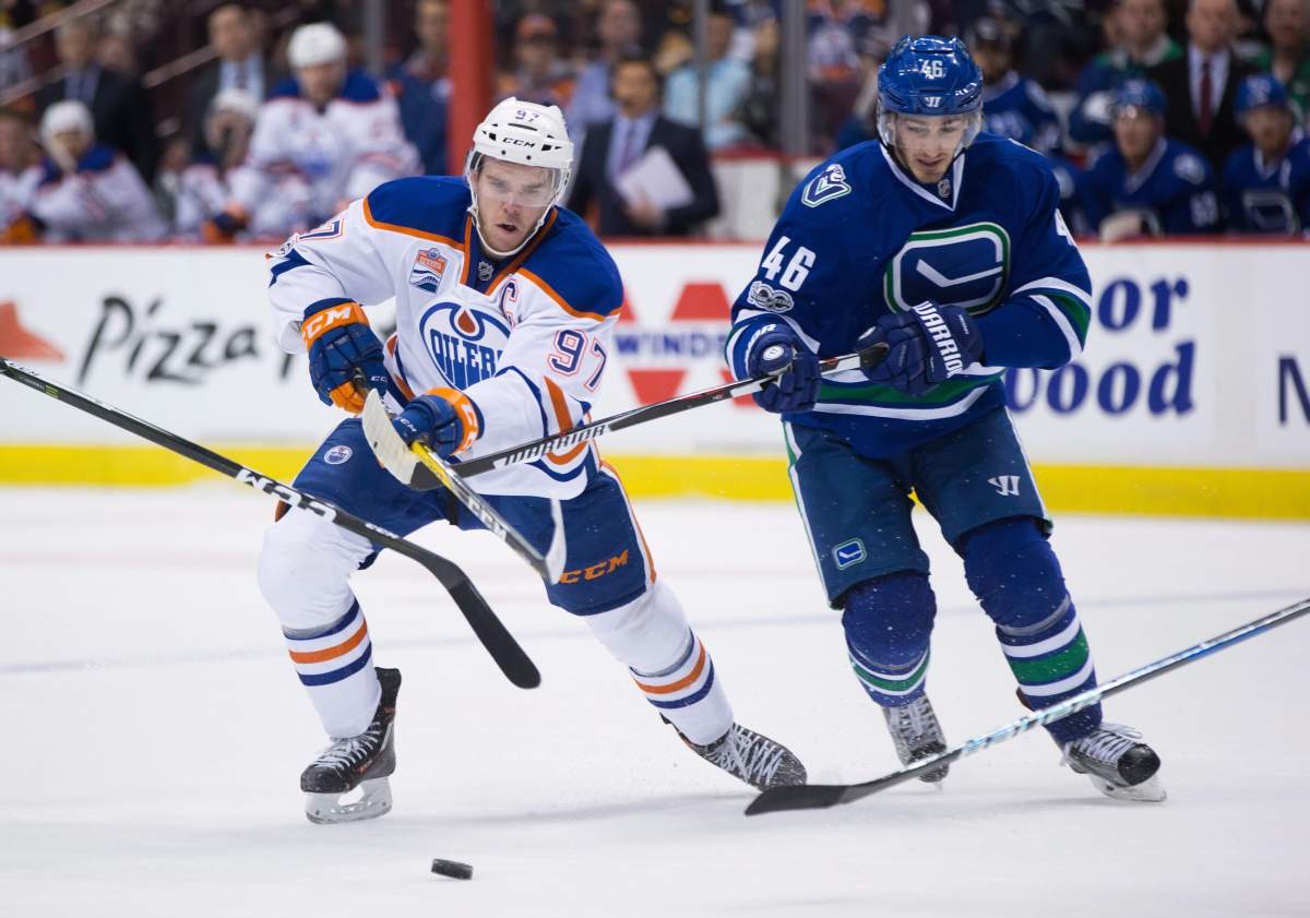 Edmonton Oilers' Connor McDavid, left, has his stick lifted by Vancouver Canucks' Jayson Megna during first period NHL hockey action in Vancouver, B.C., on Saturday, April 8, 2017. 