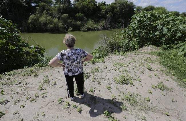 Pamela Taylor, whose home is on the south side of the border fence, stands near the Rio Grande, in Brownsville, Texas. 

