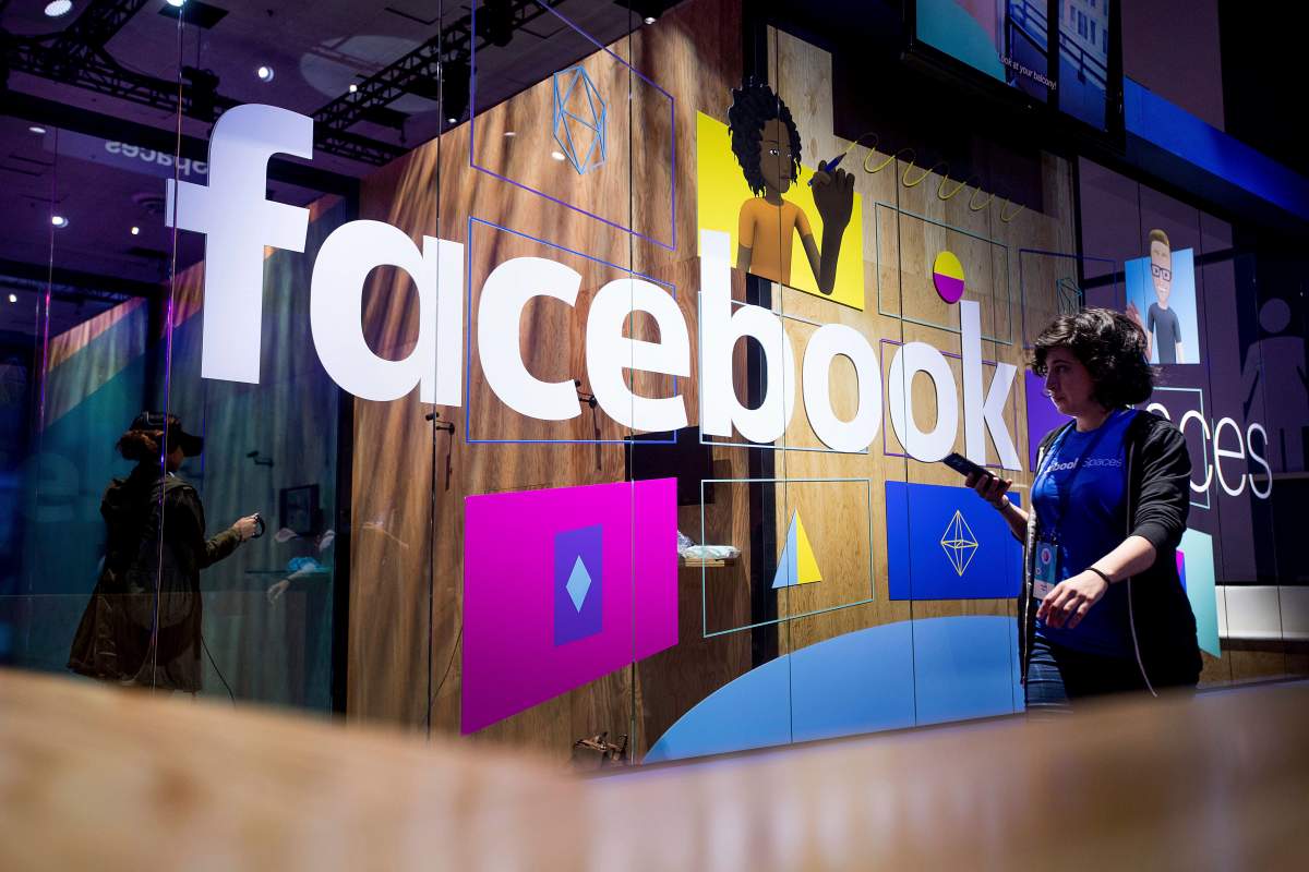 A conference worker passes a demo booth at Facebook's annual F8 developer conference, Tuesday, April 18, 2017, in San Jose, Calif. 