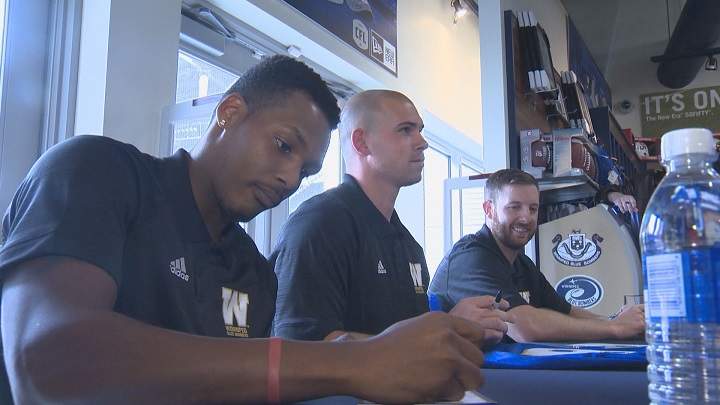 Winnipeg Blue Bombers quarterbacks Dominique Davis, Dan LeFevour and Matt Nichols sign autographs on Monday at Investors Group Field.