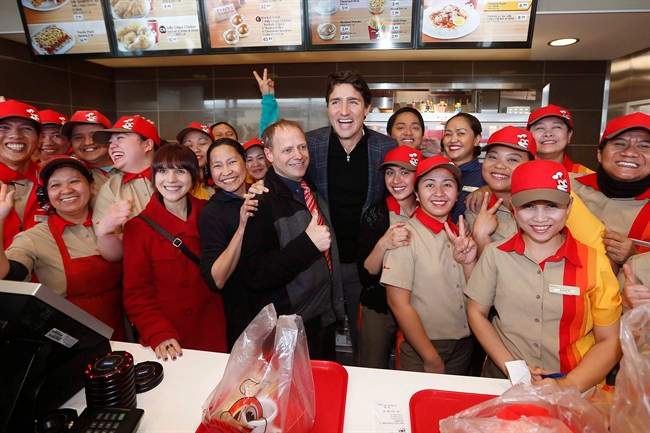Prime Minister Justin Trudeau, centre, and Manitoba MLA Cindy Lamoureux, red coat, visits with staff at a local restaurant in Winnipeg in January. 