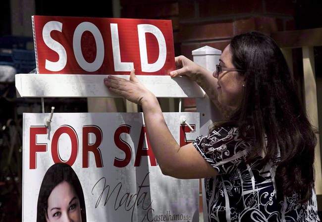 A real estate agent puts up a "sold" sign in front of a house in Toronto, Tuesday, April 20, 2010.