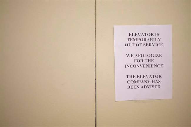 A sign is taped to a door of an elevator in a downtown Toronto office building on Wednesday, July 13, 2016. A retiree who says he hurt his leg after tumbling from a malfunctioning elevator in his downtown condominium is suing one of the world's largest elevator companies for negligence.