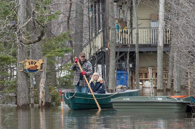 A man and woman use a boat to move along a street in the town of Rigaud, Que., west of Montreal, Thursday, April 20, 2017, following flooding in the area.