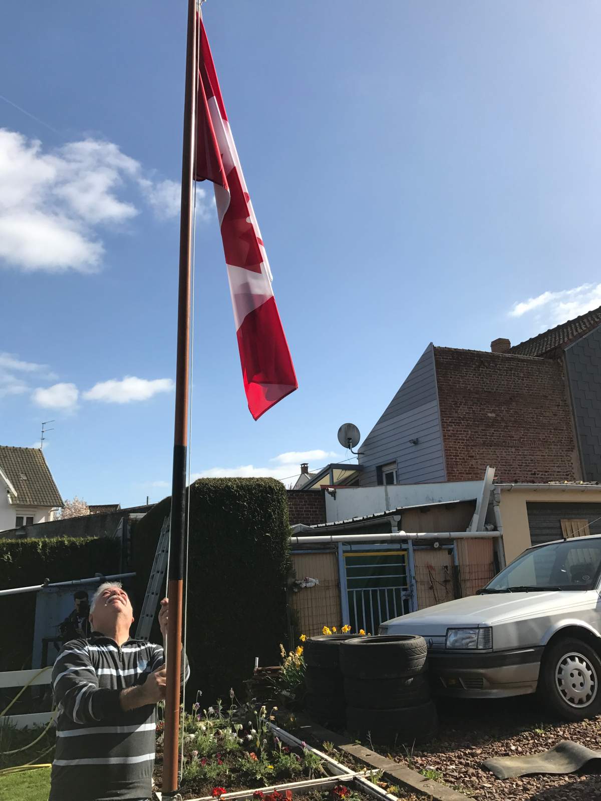 Givenchy resident Richard Bouzen erects a Canadian flag on his property.