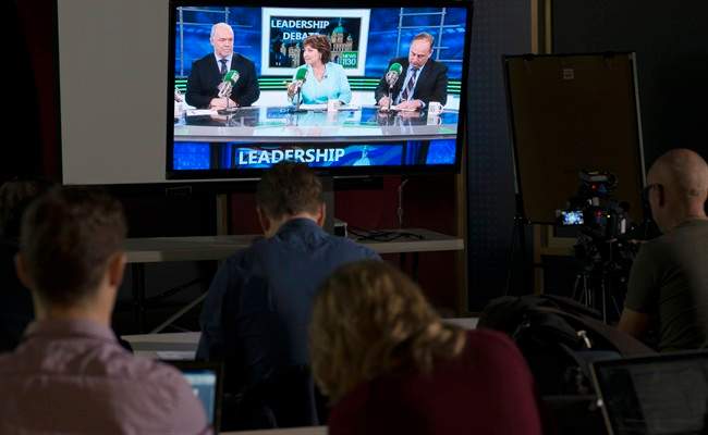 Reporters watch the British Columbia election leadership live radio debate with NDP Leader John Horgan, Liberal Leader Christy Clark and Green Party Leader Andrew Weaver on a television in Vancouver, Thursday, April 20, 2017.