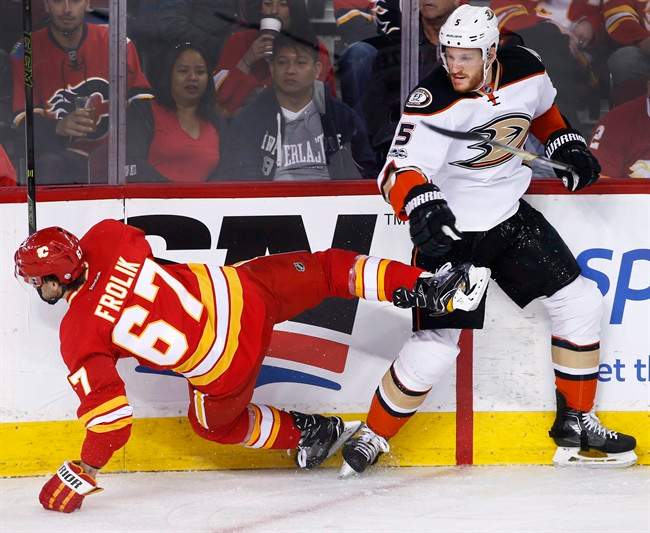 Anaheim Ducks' Korbinian Holzer, right, from Germany, knocks down Calgary Flames' Michael Frolik, from Czech Republic, during first period NHL action in Calgary, Alta., Sunday, April 2, 2017. 