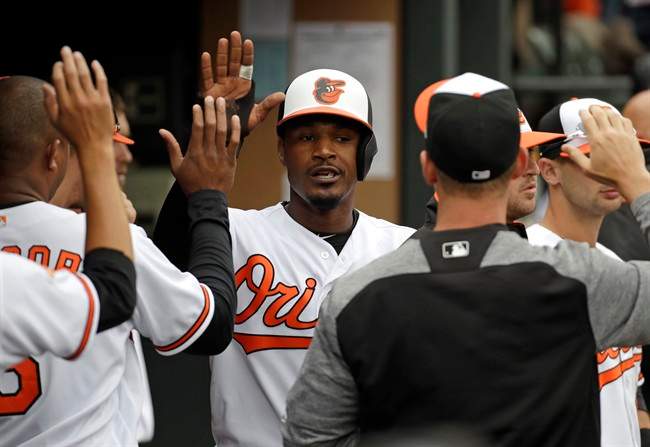 Adam Jones high-fives teammates in the dugout after scoring on a double by Mark Trumbo in the third inning of an opening-day baseball game against the Toronto Blue Jays in Baltimore.