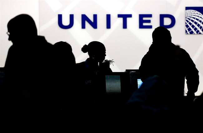 In this Saturday, Dec. 21, 2013, file photo, travelers check in at the United Airlines ticket counter at Terminal 1 in O’Hare International Airport in Chicago.