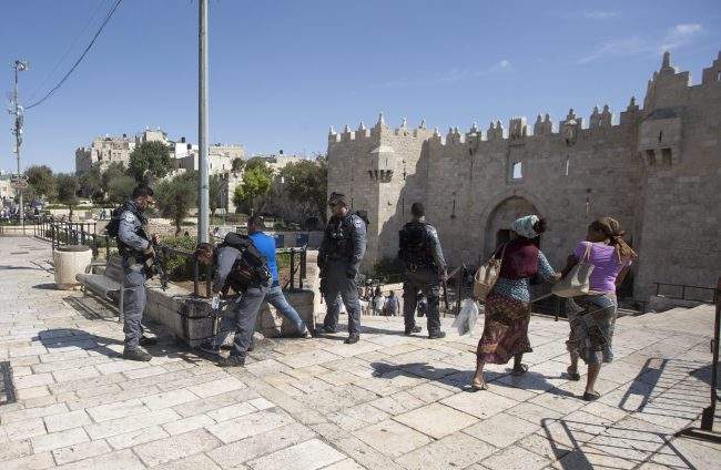 An Israeli policeman performs a body search on a Palestinian youth at Damascus gate of the old city of Jerusalem, Oct. 11, 2016. 