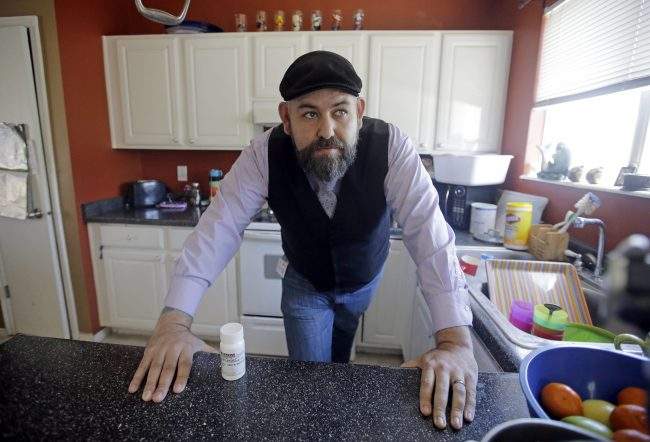 Jake Martinez looks on as he stands next to his medication at his home Thursday, May 4, 2017, in Murray, Utah.