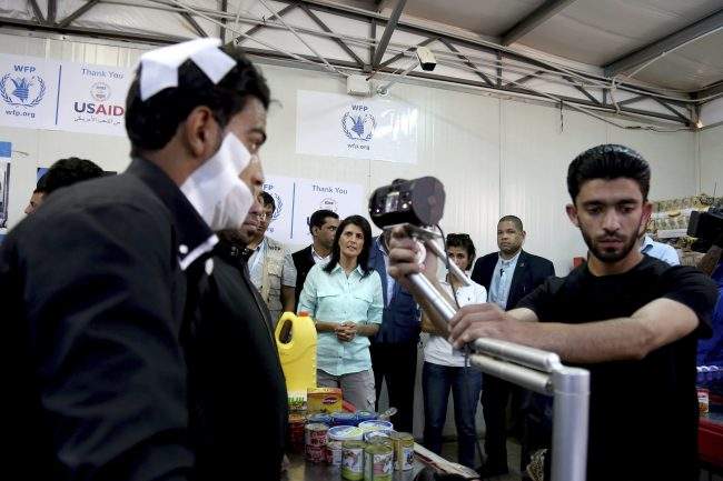 U.S. Ambassador to the United Nations Nikki Haley, background center, looks on as a bandaged Syrian refugee has his iris scanned at a supermarket, Sunday, May 21, 2017 in Zaatari Refugee Camp, Jordan. 
