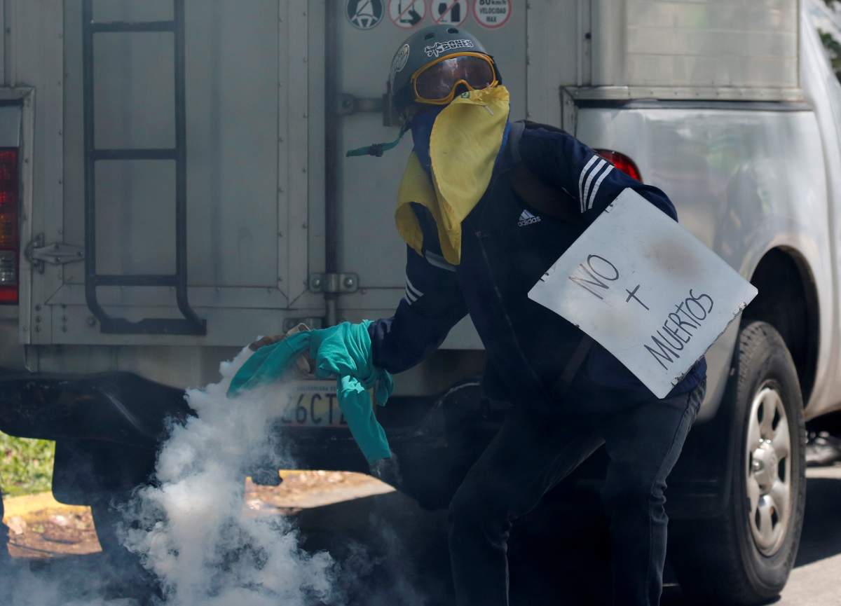 An opposition supporter clashes with riot police using a home made shield that reads “No more deads” while rallying against President Nicolas Maduro in Caracas, Venezuela, May 4, 2017.