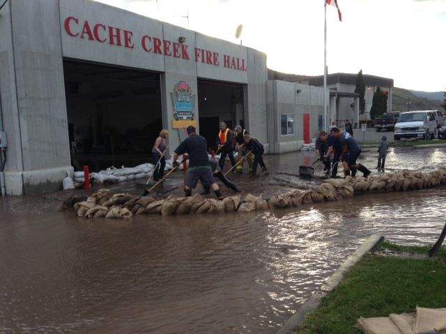 Firefighters pile up sandbags in an effort to control the flow of water at the Cache Creek Fire Hall on May 5, 2017.