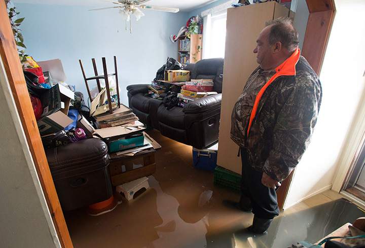Flood waters lap at his feet as Marcel Theriault looks at his living room on the main floor of his home Sunday May 7, 2017 in Gatineau, Que.