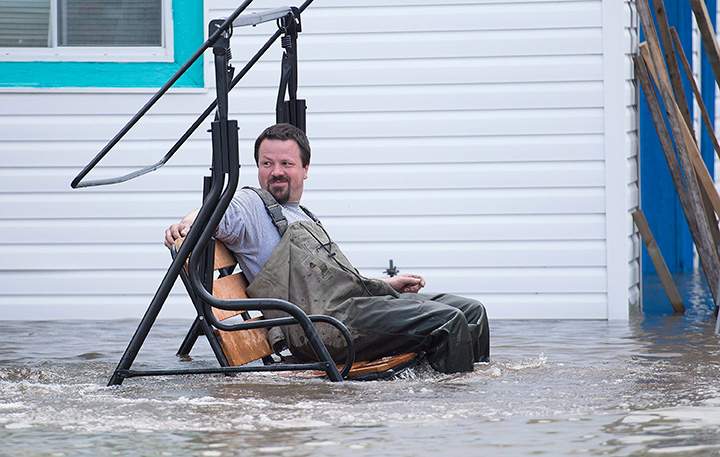 A man sits on a swing chair surrounded by floodwater in the town of Rigaud, west of Montreal, Saturday, May 6, 2017, following flooding in the region.