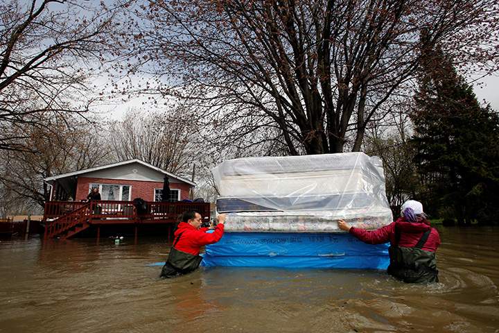 Jean-Francois Perrault (L) and Julie Theriault move mattresses from a home in a flooded residential area in Gatineau, Quebec, May 7, 2017.