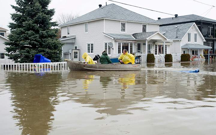 A boat passes in front of a flooded home Sunday May 7, 2017 in Gatineau, Quebec.