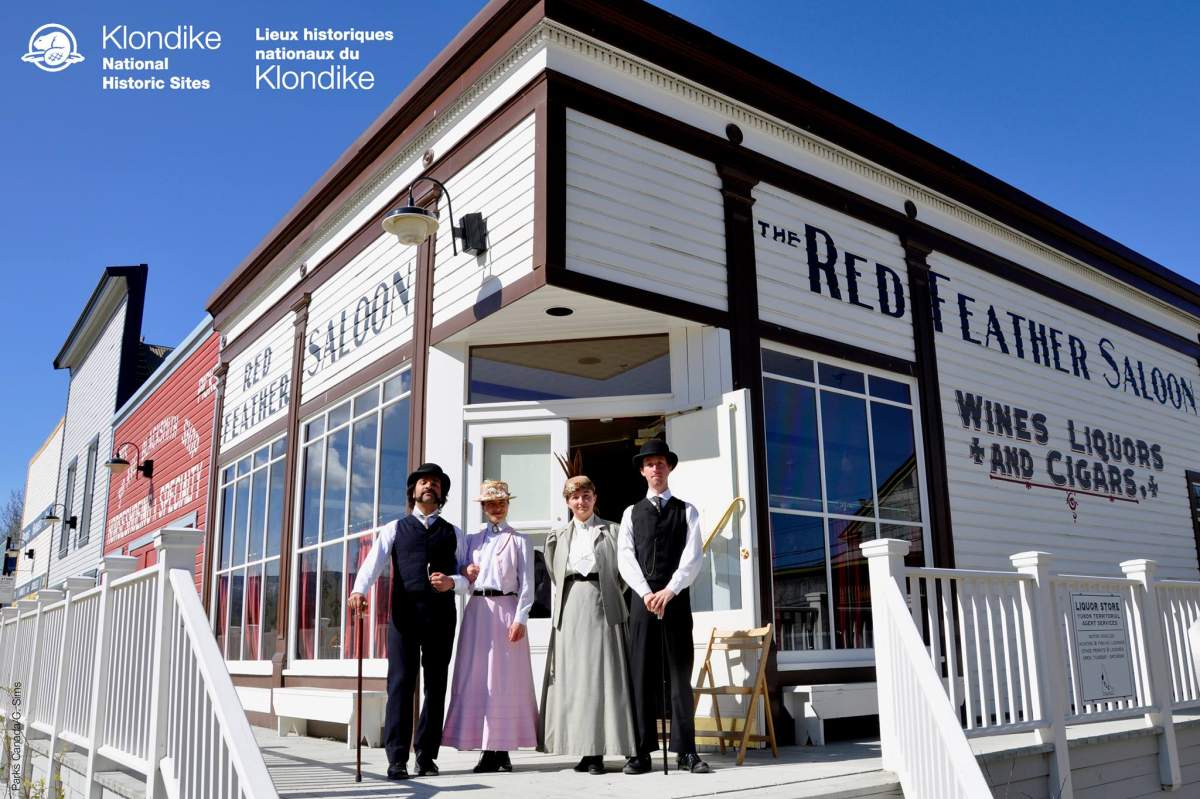 People wear traditional clothing outside historic buildings in Dawson City, Yukon.