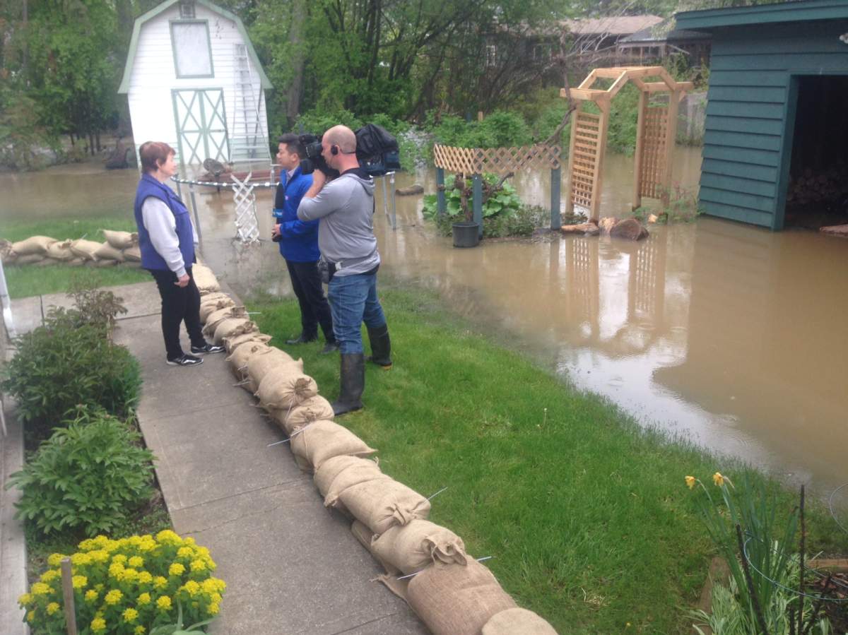 Global News interviewing a woman who has been sandbagging around her home. Credit: Jamie Forsythe.
