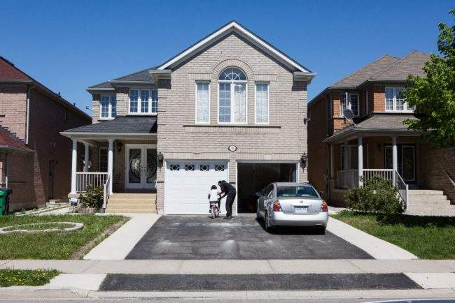 A woman helps a girl ride a bike in front of a house in Brampton, On. on May 20, 2017. 

