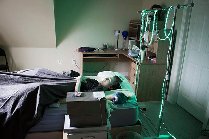 Rachael in her bedroom using green light therapy to help with the pain.