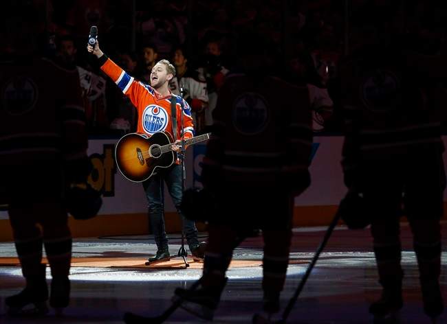 Canadian country singer Brett Kissel holds his faulty microphone asking the crowd to sing the "Star-Spangled Banner" before the start of the Anaheim Ducks and the Edmonton Oilers NHL hockey round two playoff hockey game in Edmonton, Sunday, April 30, 2017.