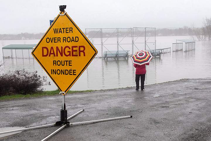 Margaret Wicken stops to take a photo of Morrell Park which is completely covered with flood water from the St. John River in Fredericton, N.B., on Saturday, May 6, 2017.