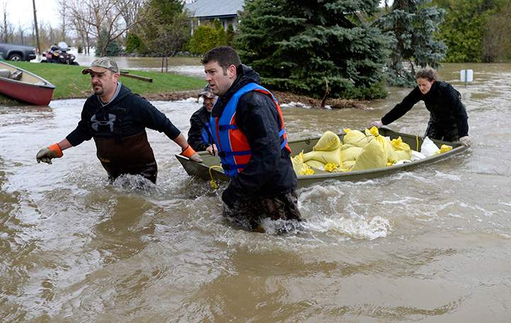 Volunteers wade through water to get sandbags to homes on Voisine Road in Rockland, Ont., about 40 kilometres east of Ottawa on Sunday, May 7, 2017.