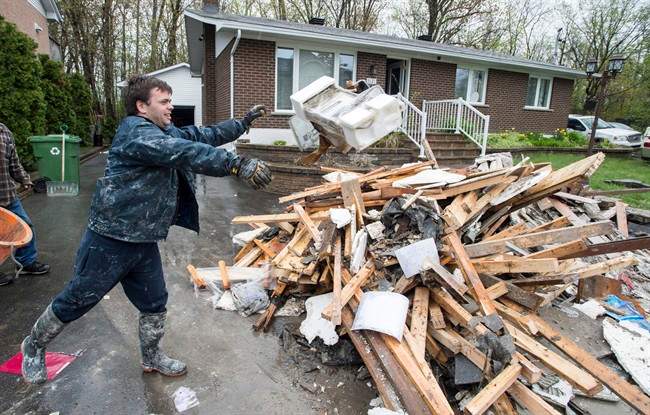 David Samuelson throws debris from his flooded house onto a pile on his driveway in the Pierrefonds borough of Montreal Sunday, May 14, 2017.  Montreal firefighters announced a fundraising blitz to help victims dealing with the aftermath of May's devastating floods. Tuesday, June 13, 2017.
