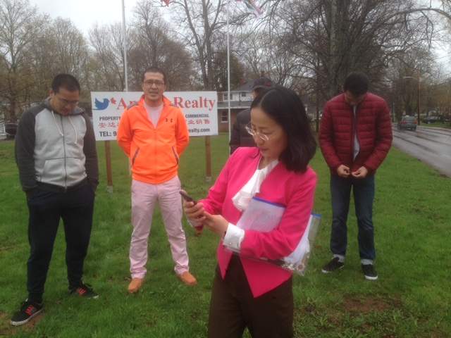 Jie Hu, PEI's first Chinese real estate broker, works the phone. Some of her clients stand behind her.