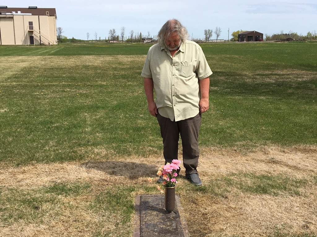 Kap Palmer stands over his mother\’s grave where truck tracks can be seen.