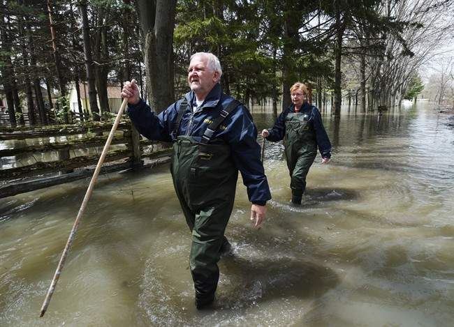 Paul and Suzanne Diamond walk through the floodwaters from Lac-Saint-Pierre to check on their cottage Saturday, May 13, 2017 in Yamachiche, Que.